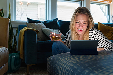 Relaxed woman with wine looking at tablet at home