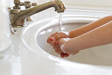 Close-up of girl (6-7) washing hands