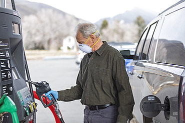 Man wearing surgical gloves and mask at gas station