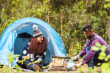 Man using rock to hammer tent peg