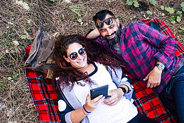 Smiling couple lying on blanket using tablet