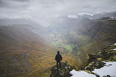 Man standing on Dalsnibba mountain overlooking valley in Geiranger, Norway