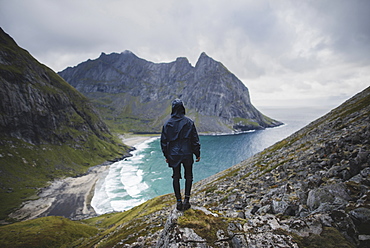 Man standing on rock by Kvalvika Beach in Lofoten Islands, Norway