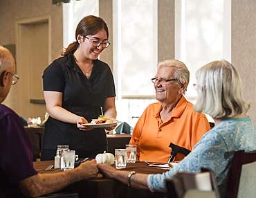 Smiling waitress handing food to smiling senior man