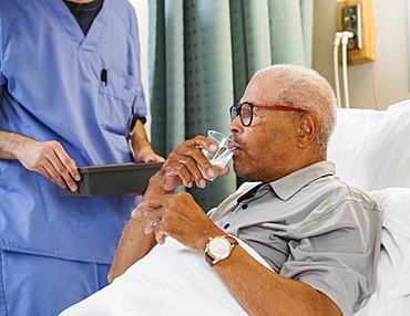 Senior man drinking water in bed