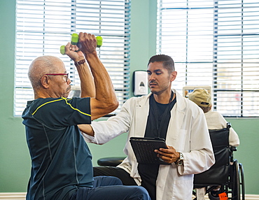 Senior man lifting dumbbells at rehabilitation center