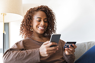 Smiling woman holding credit card and smart phone