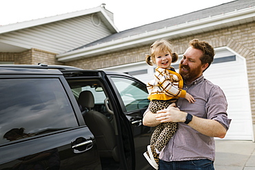 Father and daughter (2-3) standing next to mini van