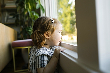 Girl (2-3) looking through window