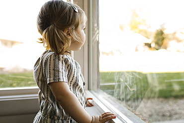 Girl (2-3) looking through window