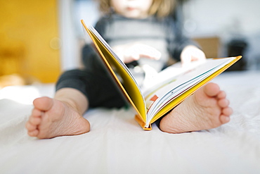 Barefoot girl (2-3) reading book