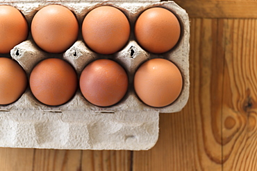 Eggs in carton on wooden table 