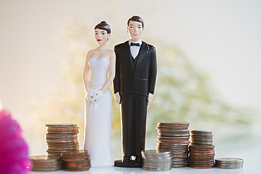 Bride and Groom cake toppers next to stacks of coins 