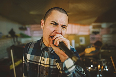 Young man singing during rehearsal in garage