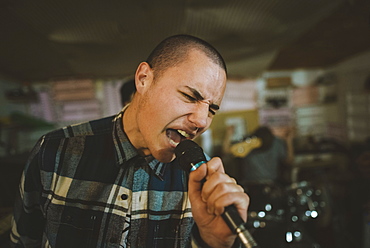 Young man singing during rehearsal in garage