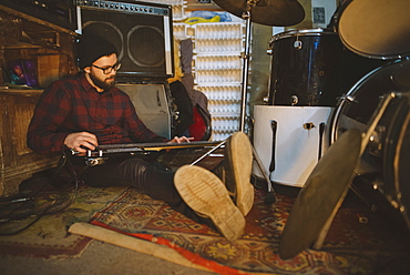 Young man playing bass guitar during rehearsal in garage