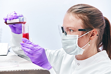 Female technician pouring liquid into vial