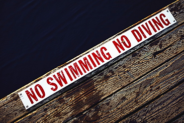 No swimming No diving sign at the edge of wooden jetty