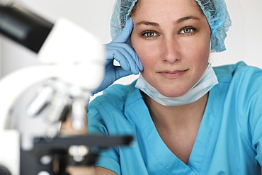 Portrait of laboratory technician next to microscope