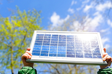 Close-up of boys (4-5) hands holding solar panel against sky