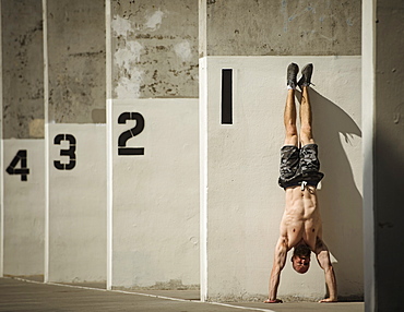 Man doing handstand next to wall