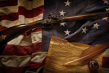 Rifle and US constitution lying on American flag