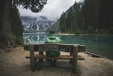 Italy, Man sitting on bench looking at Pragser Wildsee