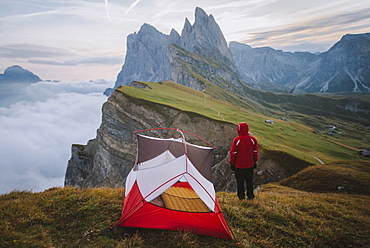 Italy, Dolomite Alps, Seceda mountain, Man standing near tent looking at scenic view of Seceda mountain in Dolomites