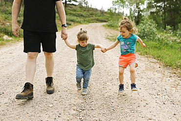 Father and daughters (2-3) holding hands during walk