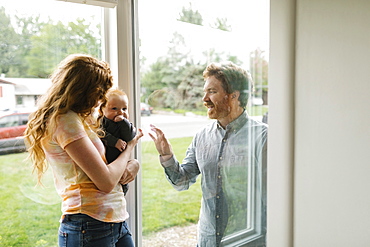 Father visiting partner and son (6-11 months) through window