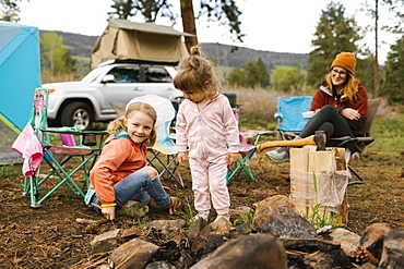 USA, Utah, Uninta Wasatch Cache National Forest, Mother looking at daughters (2-3, 6-7) playing on campsite