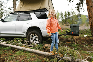 USA, Utah, Uninta Wasatch Cache National Forest, Girl (6-7) standing on log by car