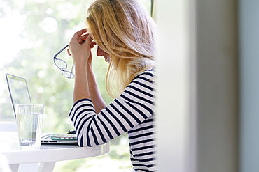 Woman using laptop and experiencing headache