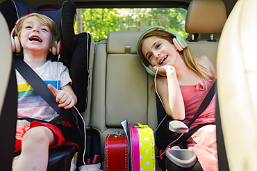 Boy (4-5) and girl (6-7) listening to music in car