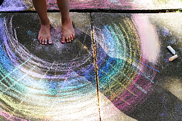 Low section of girl (6-7) standing on chalk drawing on pavement