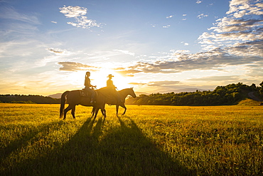 USA, Utah, Salem, Father and daughter (14-15) riding horses at sunset