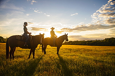 USA, Utah, Salem, Father and daughter (14-15) riding horses at sunset