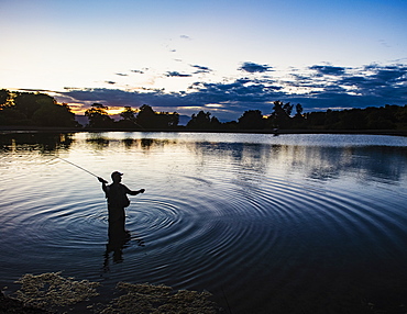 USA, Utah, Salem, Silhouette of man fly fishing in lake at dusk