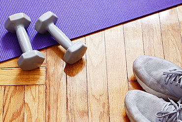 Weights, yoga mat and running shoes on floor