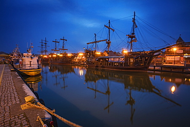 Poland, Pomerania, Leba, Historic tall ships moored at harbour at dusk