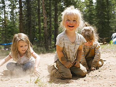 Three smiling girls (2-3, 4-5) playing in sand on camping, Wasatch-Cache National Forest