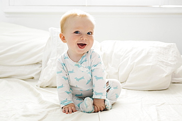 Baby boy (6-11 months) lying on bed