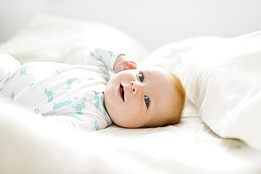 Baby boy (6-11 months) lying on bed