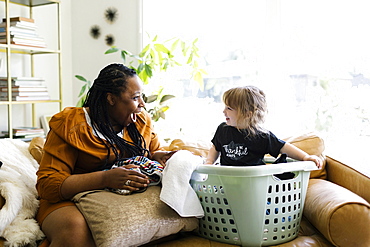 Woman playing with little girl (2-3) sitting in laundry basket