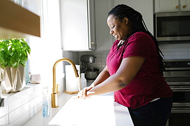 Woman washing hands in kitchen sink