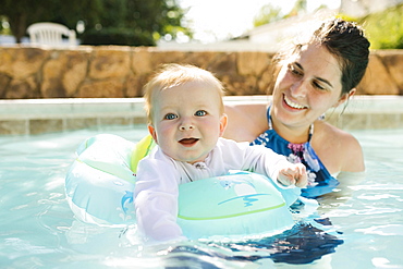 Mother with baby son (6-11months) playing in outdoor swimming pool