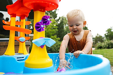 Baby boy(18-23 months) playing with water toys in garden