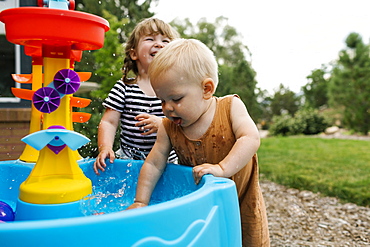 Toddler girl (2-3) and baby boy (18-23 months) playing in garden