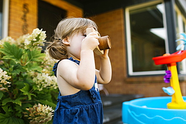 Toddler girl (2-3) with toy camera in garden