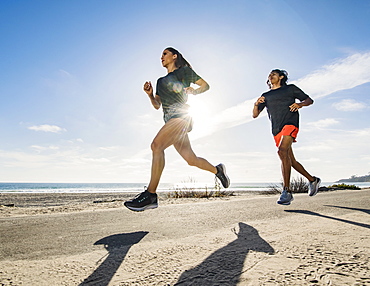 USA, California, Dana Point, Man and woman running together by coastline